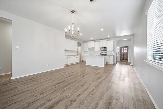a kitchen with wooden floors white cabinets and stainless steel appliances