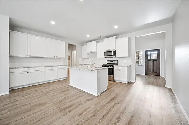 a large kitchen with cabinets wooden floor and stainless steel appliances