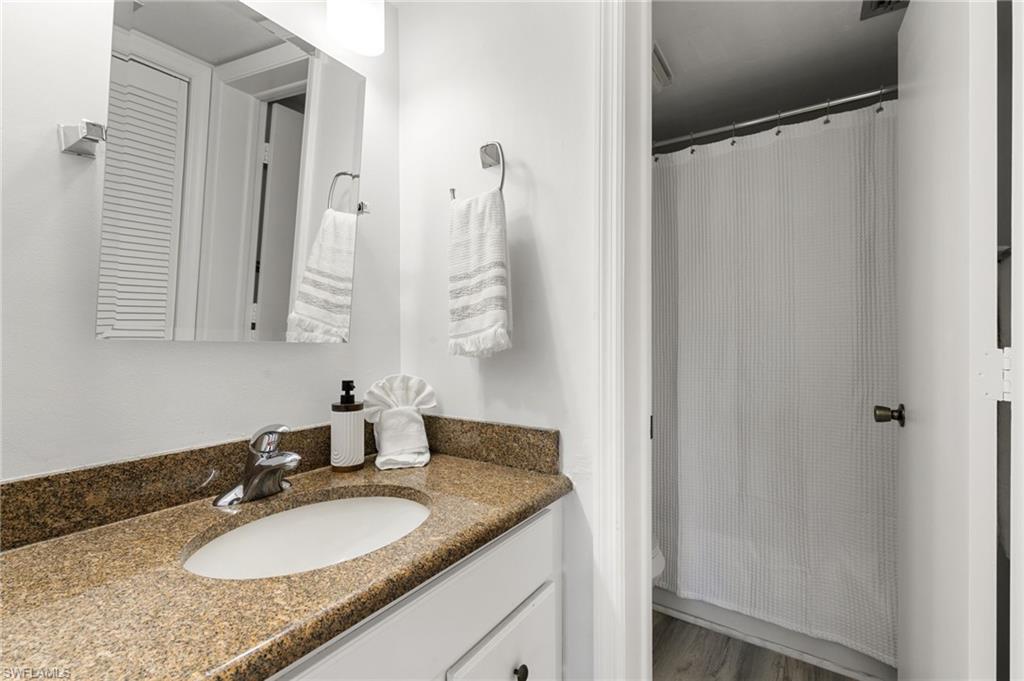 600 Neapolitan Way, Unit 257 Naples, FL 34103 - Photo 14 of 35 a bathroom with a granite countertop sink and a mirror