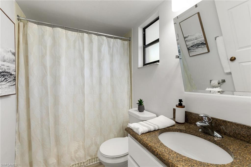 600 Neapolitan Way, Unit 257 Naples, FL 34103 - Photo 16 of 35 a bathroom with a granite countertop sink mirror vanity and toilet