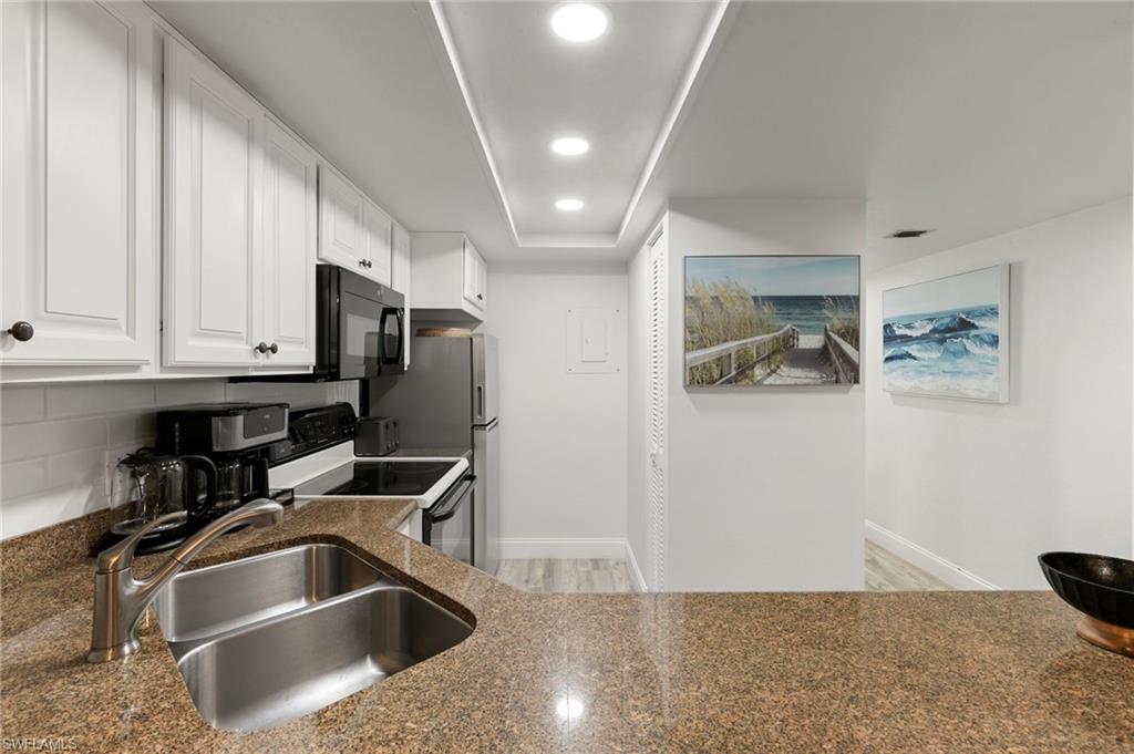 600 Neapolitan Way, Unit 257 Naples, FL 34103 - Photo 9 of 35 a kitchen with stainless steel appliances granite countertop a sink and a refrigerator