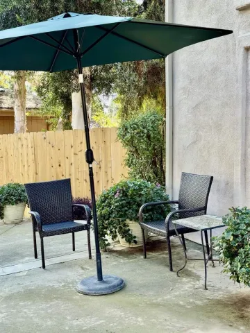 a view of a chairs and table under an umbrella in backyard