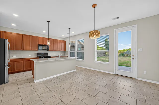 a kitchen with stainless steel appliances granite countertop a stove a sink and a refrigerator