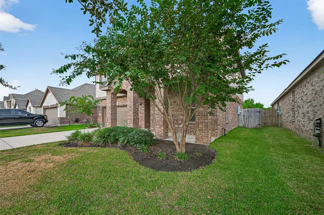 a view of a house with a yard and a large tree