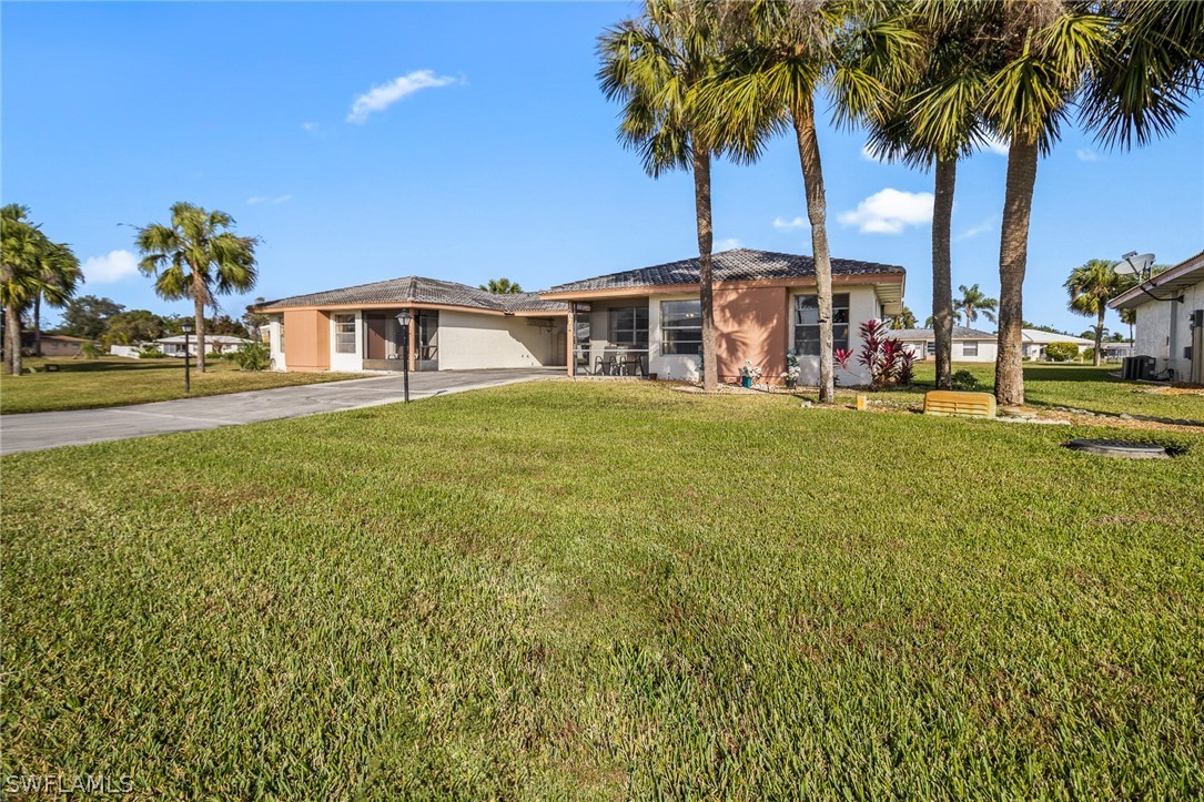 1609 Ridgecrest Street Lehigh Acres, FL 33936 - Photo 16 of 20 a front view of a house with a garden and palm trees