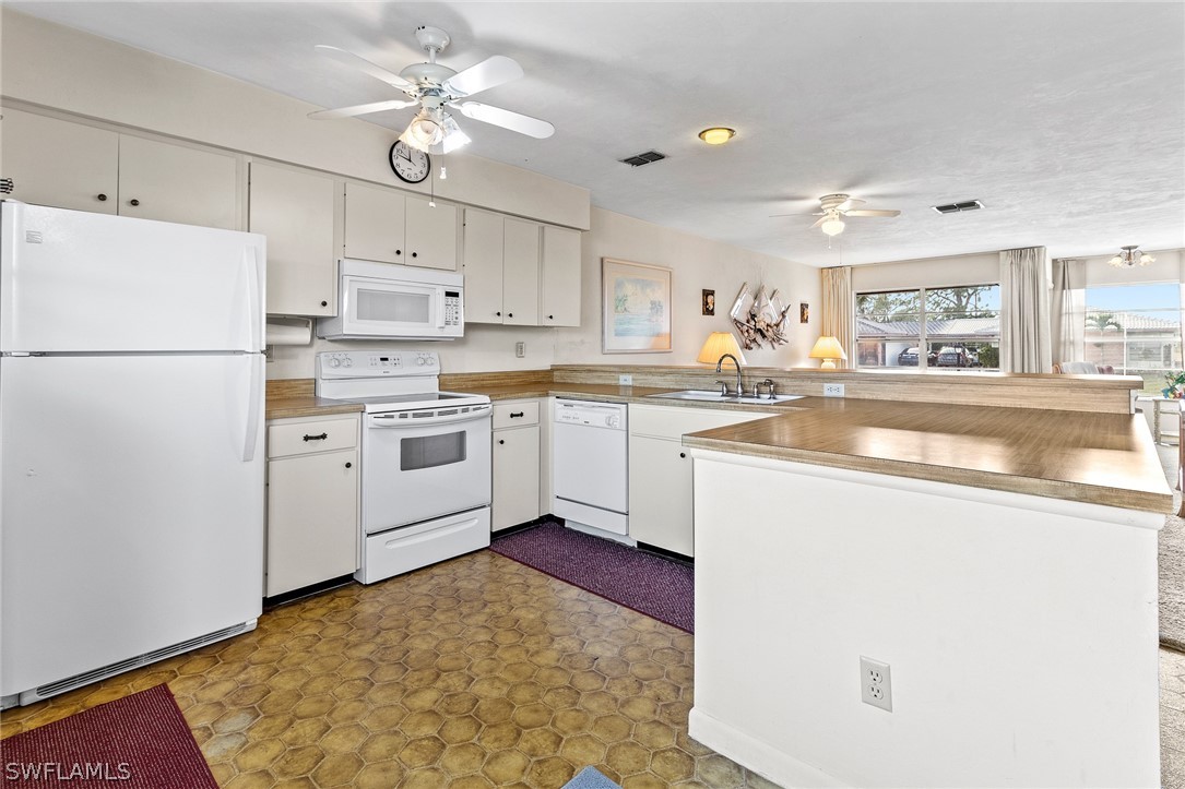 1609 Ridgecrest Street Lehigh Acres, FL 33936 - Photo 5 of 20 a kitchen with a sink a stove a refrigerator and white cabinets