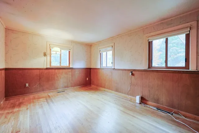 an empty room with wooden floor and windows