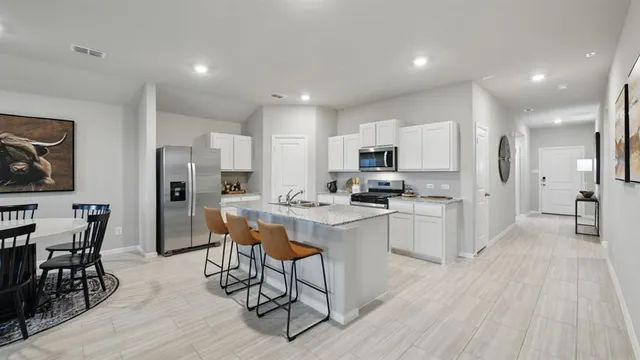 a kitchen with a stove top oven a sink a refrigerator and white cabinets
