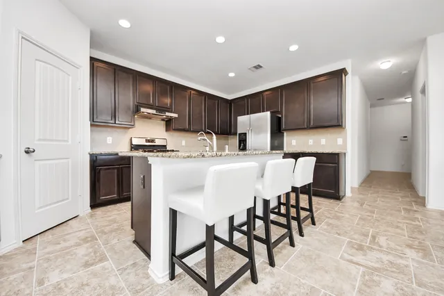 a kitchen with kitchen island granite countertop wooden cabinets and refrigerator