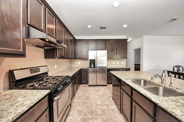 a kitchen with granite countertop a sink stove and refrigerator