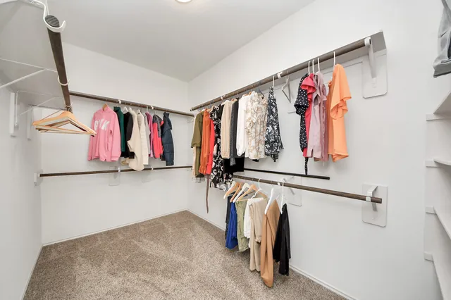 a view of walk in closet with clothes and shoes