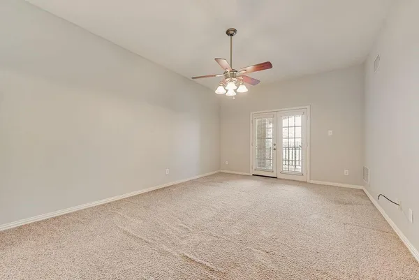 an empty room with chandelier fan and windows