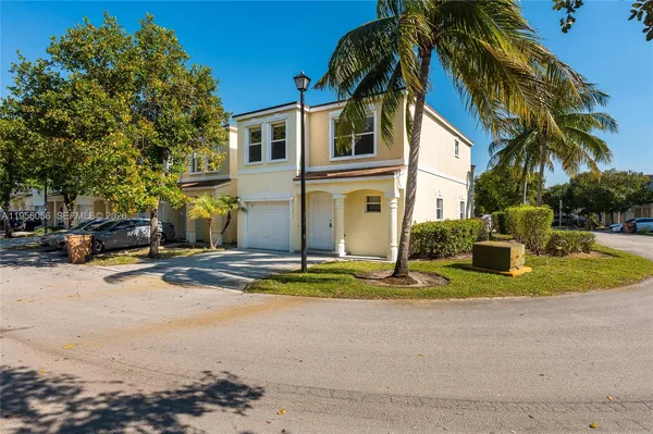 a view of a white house with a yard and palm trees