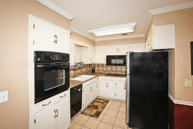 a kitchen with granite countertop white cabinets and refrigerator