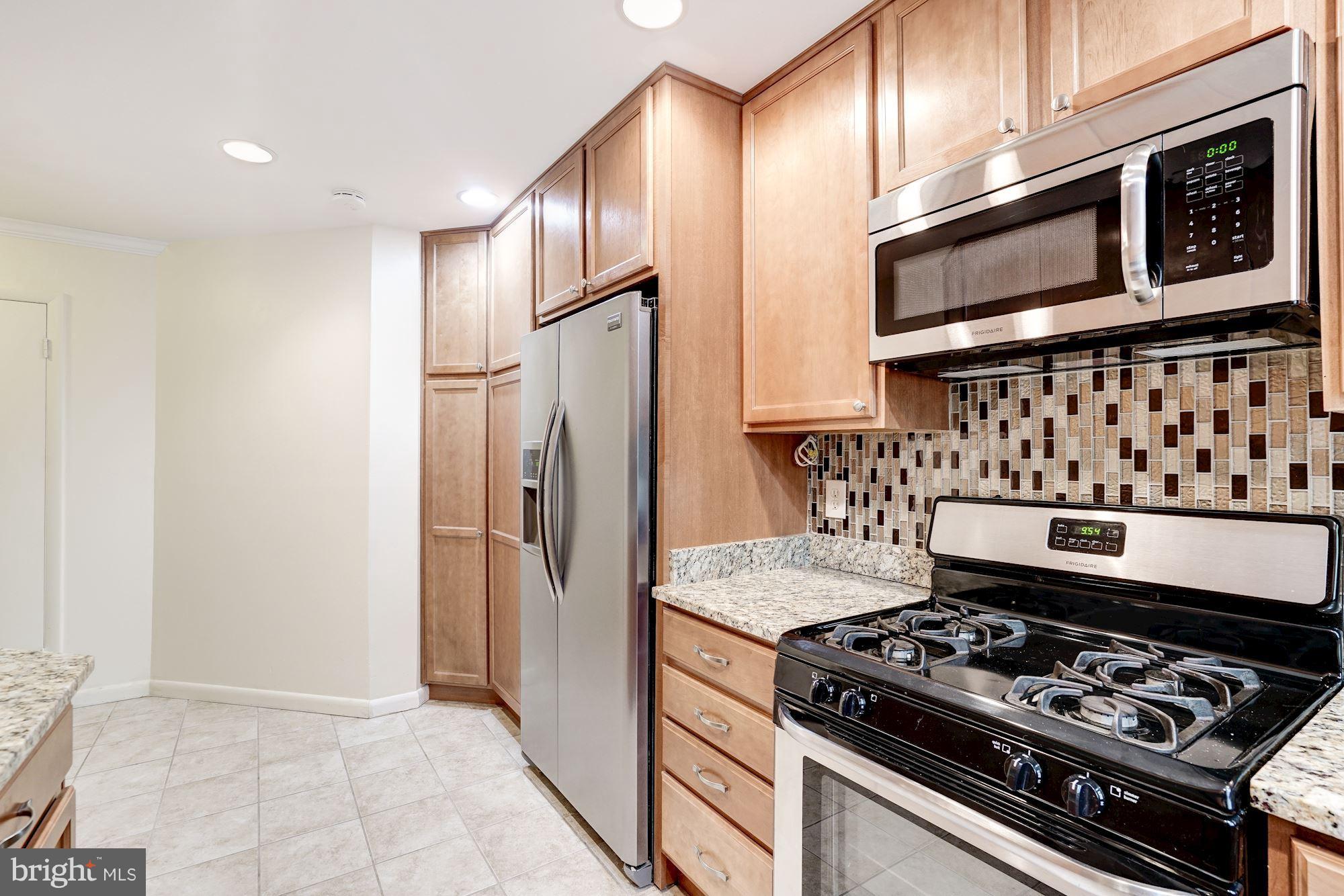 11089 Saffold Way Reston, VA 20190 - Photo 11 of 30 a kitchen with stainless steel appliances granite countertop a stove and a refrigerator