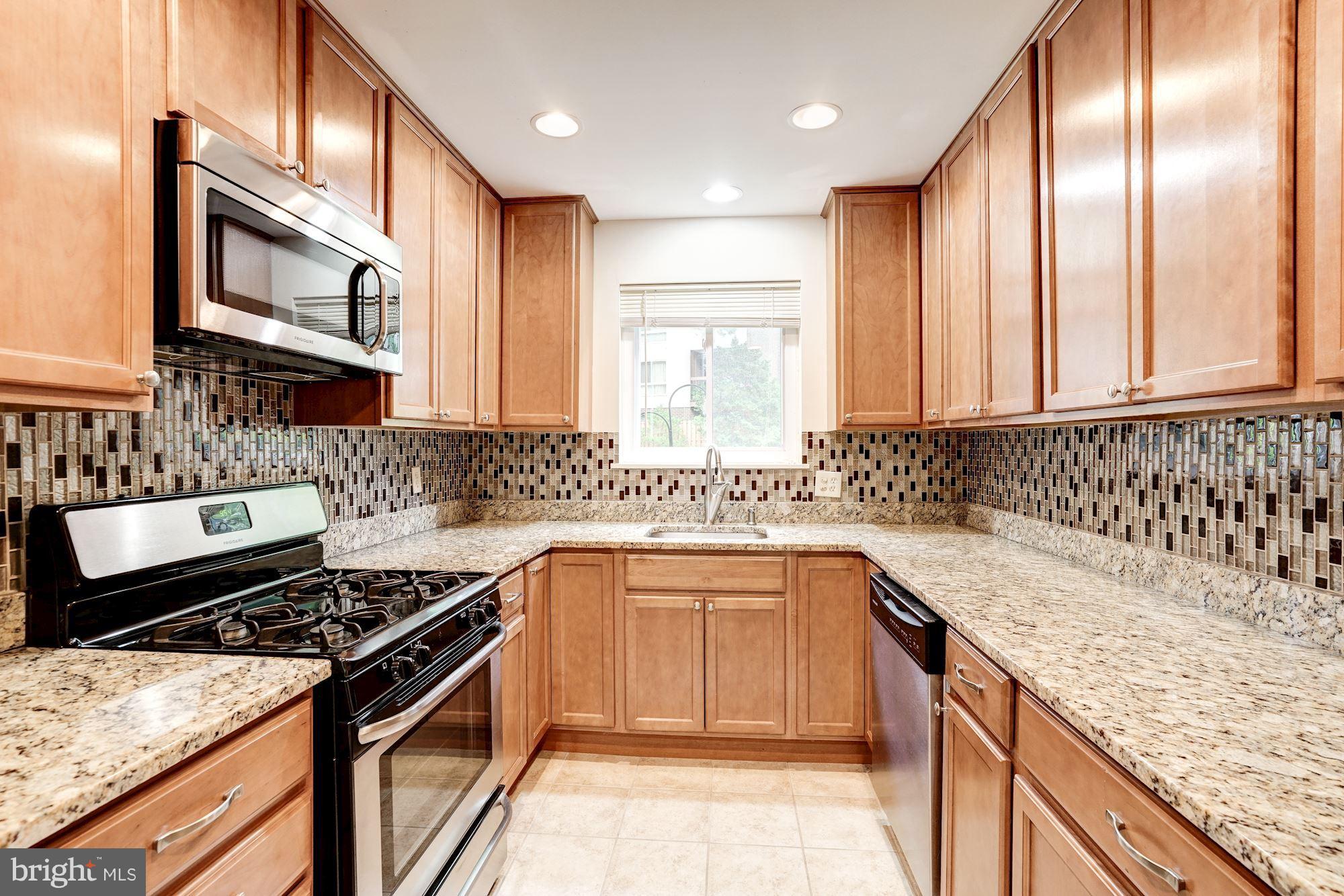 11089 Saffold Way Reston, VA 20190 - Photo 12 of 30 a kitchen with stainless steel appliances granite countertop a sink stove and cabinets