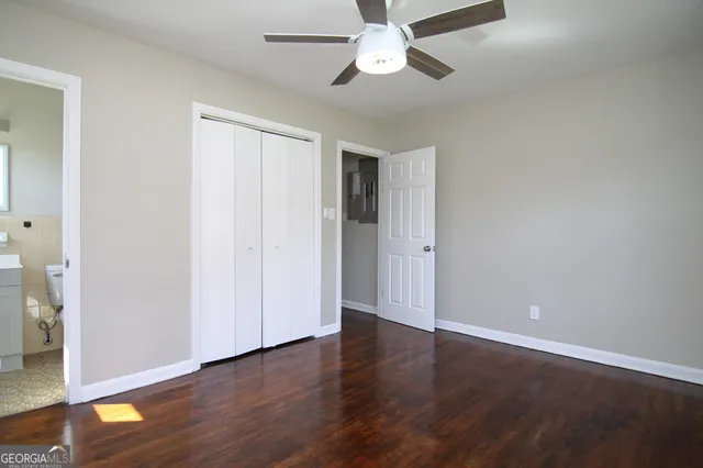 an empty room with wooden floor closet and windows