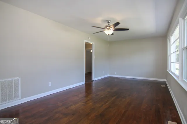 an empty room with wooden floor fan and windows