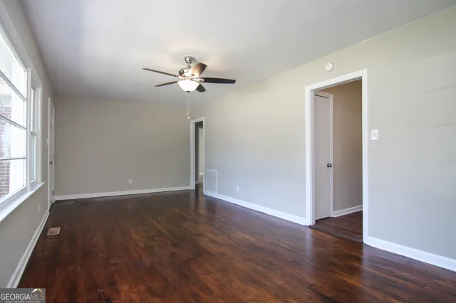 a view of an empty room with wooden floor and a window
