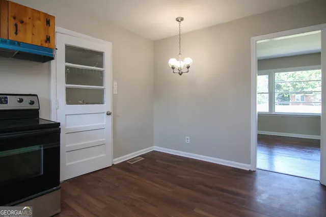 an empty room with wooden floor closet and windows