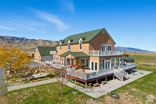4768 East Hickman Canyon Road Stockton, UT 84071 - Photo 2 of 85 South west corner of home featuring french doors, stucco siding, a deck with mountain view, a yard, and stairs.