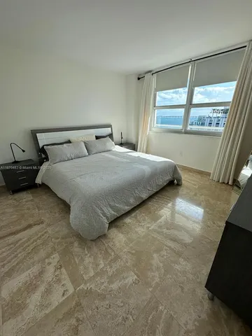 a large bed sitting in a bedroom next to a window