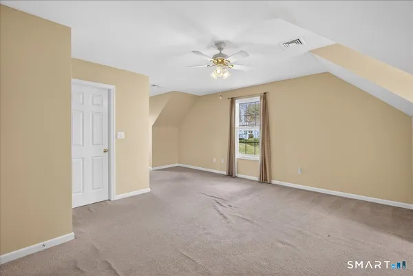 an empty room with chandelier fan and windows