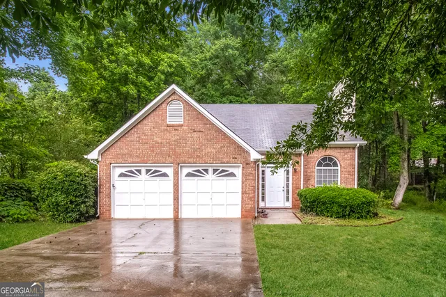 a view of a house with a yard plants and large tree
