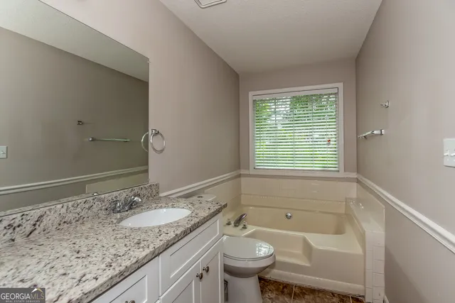 a bathroom with a toilet sink vanity and mirror