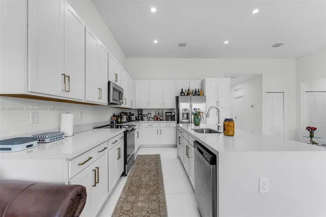 a kitchen with granite countertop a sink stainless steel appliances and white cabinets