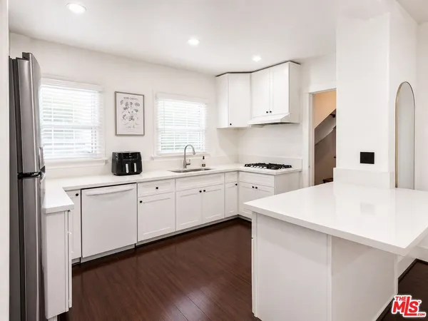 a kitchen with a sink white cabinets and white appliances