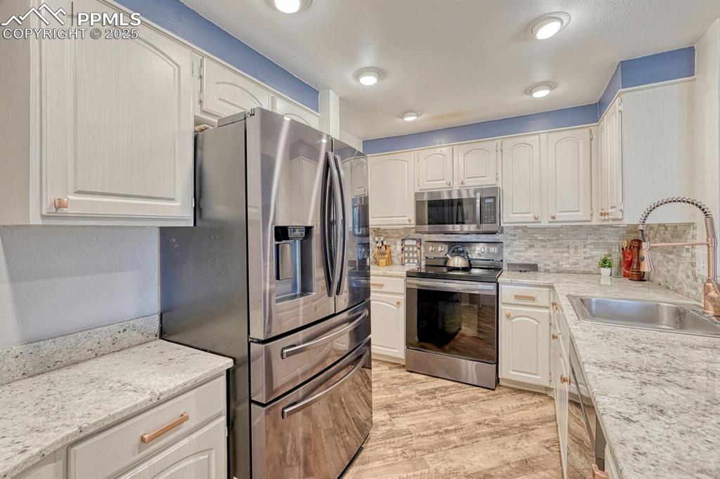 1661 Deer Creek Road Monument, CO 80132 - Photo 7 of 48 Kitchen with LVP, granite countertops, travertine backsplash
