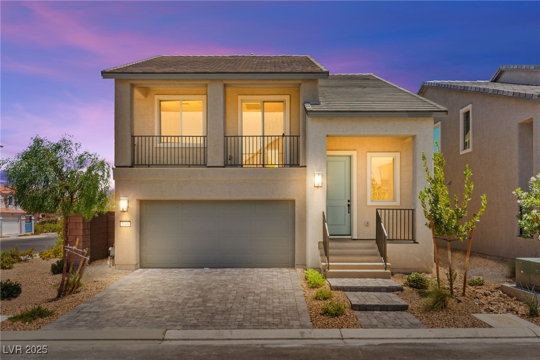 5606 Spring Trellis Street Las Vegas, NV 89113 - Photo 1 of 44 View of front of house with stucco siding, a balcony, driveway, and an attached garage