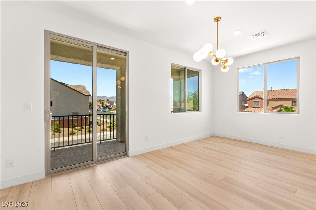 5606 Spring Trellis Street Las Vegas, NV 89113 - Photo 17 of 44 Unfurnished room with healthy amount of natural light, a chandelier, and wood finished floors