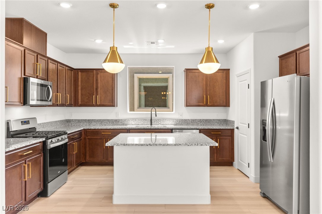 5606 Spring Trellis Street Las Vegas, NV 89113 - Photo 21 of 44 Kitchen with stainless steel appliances, light wood-style floors, light stone counters, recessed lighting, and pendant lighting