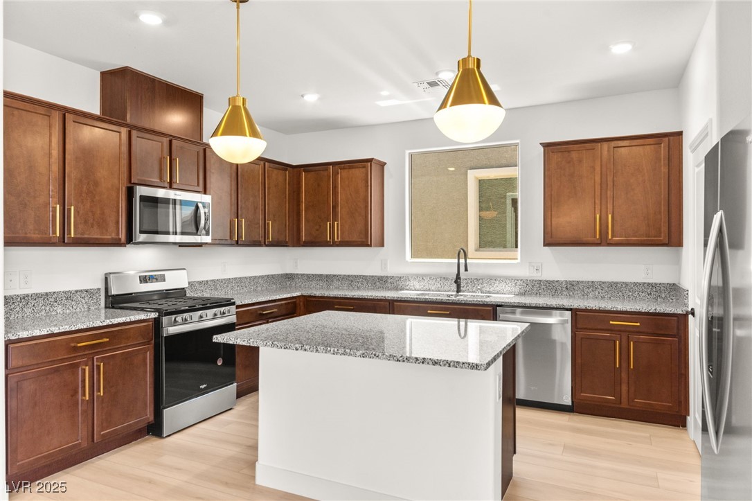 5606 Spring Trellis Street Las Vegas, NV 89113 - Photo 22 of 44 Kitchen with appliances with stainless steel finishes, light wood-type flooring, light stone counters, decorative light fixtures, and recessed lighting