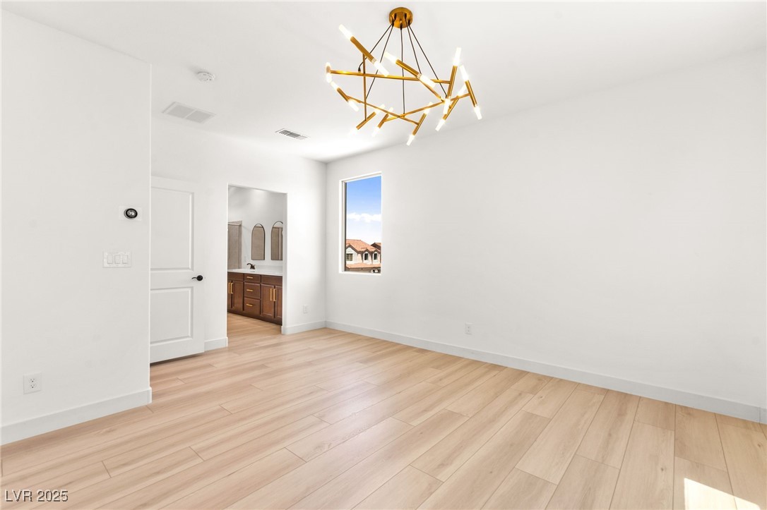 5606 Spring Trellis Street Las Vegas, NV 89113 - Photo 27 of 44 Empty room featuring a chandelier and light wood finished floors