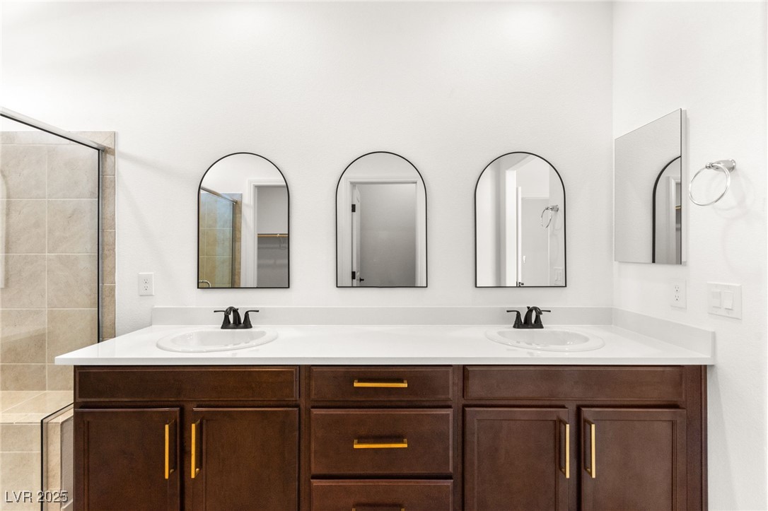 5606 Spring Trellis Street Las Vegas, NV 89113 - Photo 28 of 44 Bathroom with double vanity and a tile shower