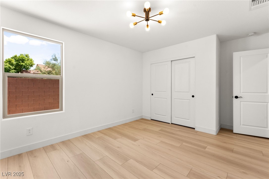 5606 Spring Trellis Street Las Vegas, NV 89113 - Photo 34 of 44 Unfurnished bedroom with a chandelier, light wood-type flooring, and a closet