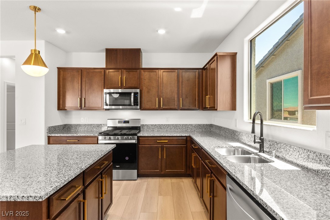 5606 Spring Trellis Street Las Vegas, NV 89113 - Photo 5 of 44 Kitchen with appliances with stainless steel finishes, light wood-type flooring, light stone counters, hanging light fixtures, and recessed lighting