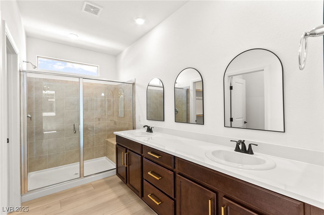 5606 Spring Trellis Street Las Vegas, NV 89113 - Photo 9 of 44 Bathroom with a stall shower, double vanity, and wood finished floors