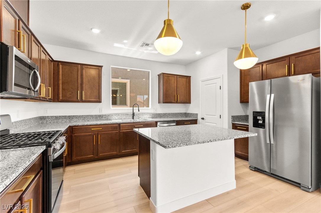 5606 Spring Trellis Street Las Vegas, NV 89113 - Photo 10 of 44 Kitchen with stainless steel appliances, light stone counters, decorative light fixtures, and recessed lighting