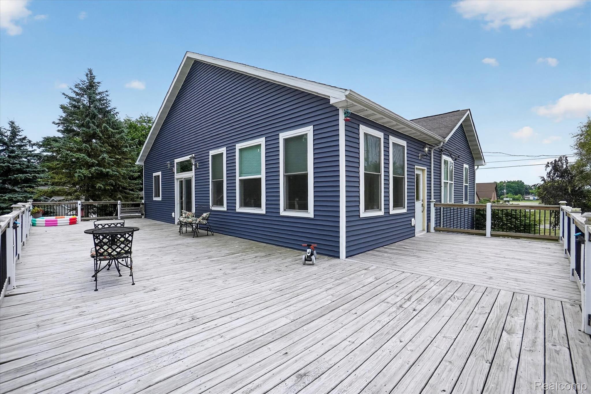 6524 Kelly Road Flushing, MI 48433 - Photo 39 of 47 Expansive exterior deck featuring a white railing system, blue horizontal siding, white trim, and multiple windows