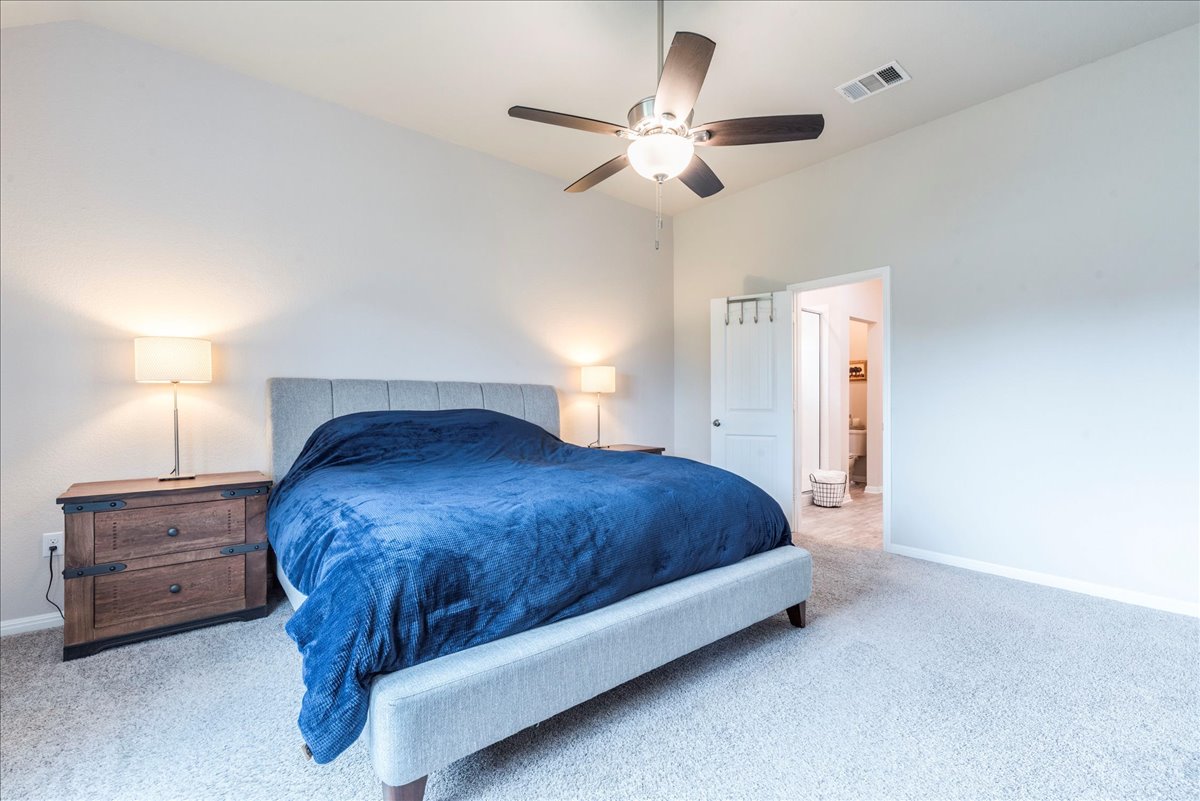 125 Groesbeck Lane Leander, TX 78641 - Photo 15 of 38 a bedroom with a bed and a chandelier