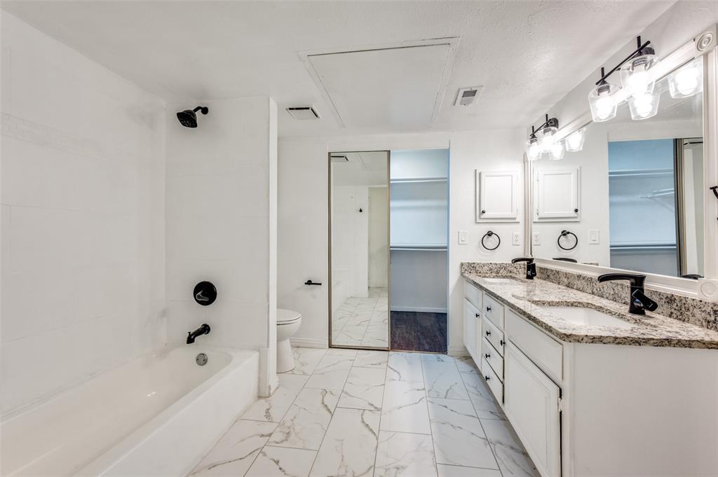 5550 Spring Valley Road, Unit E22 Dallas, TX 75254 - Photo 8 of 14 a bathroom with a granite countertop sink a mirror and a bathtub