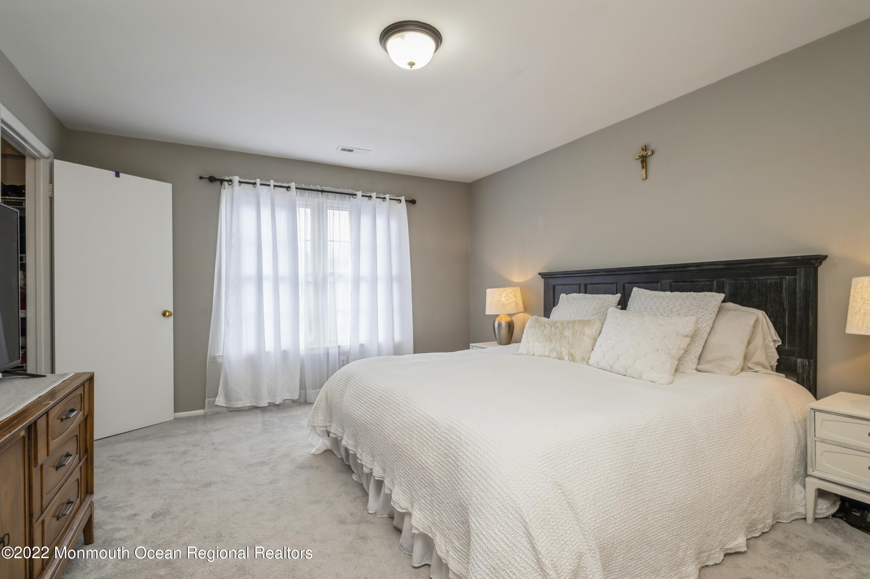 503 Harding Road, Unit 5 Freehold, NJ 07728 - Photo 12 of 21 a bedroom with a large bed and a flat tv screen on dresser