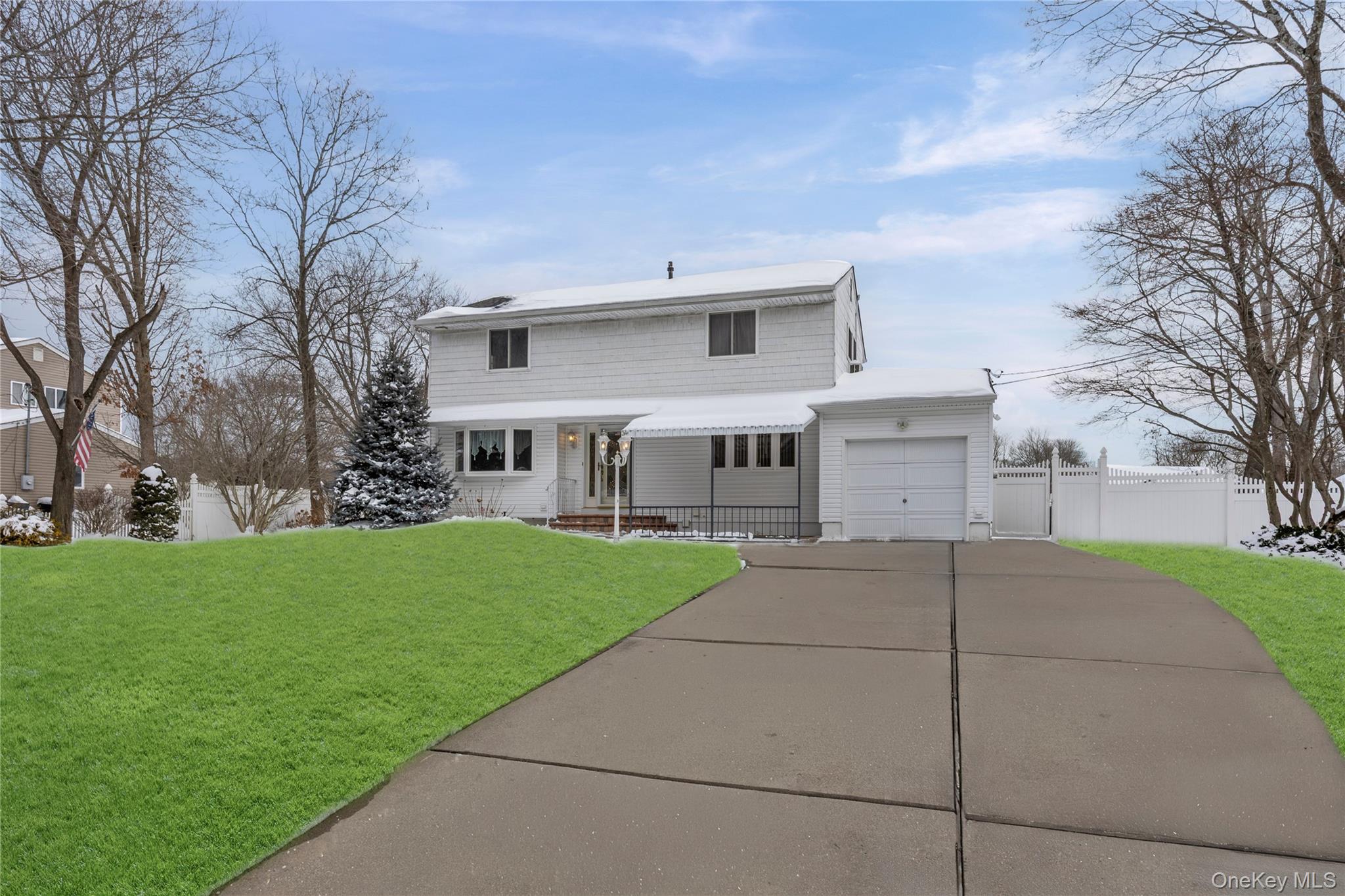 a view of a white house next to a yard with big trees