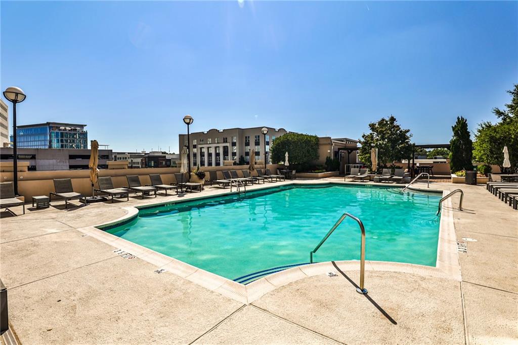 325 East Paces Ferry Road Northeast, Unit 1105 Atlanta, GA 30305 - Photo 28 of 36 a view of a swimming pool with a table and chairs