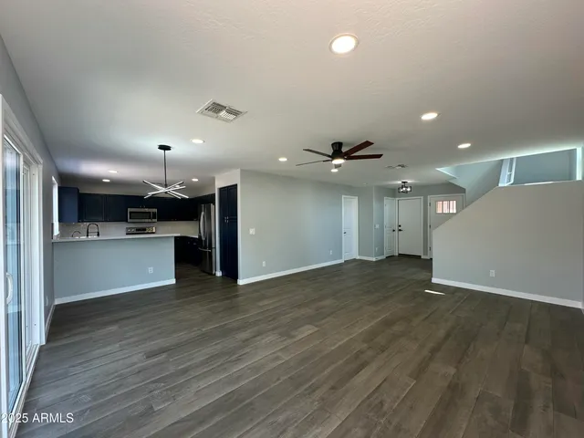 a view of a room with wooden floor a ceiling fan and windows