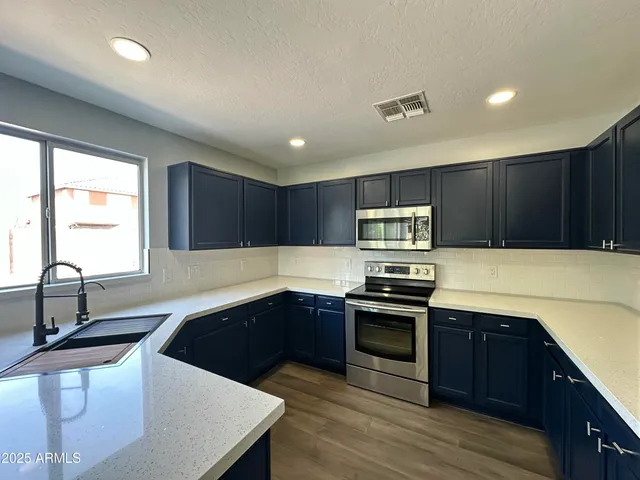 a kitchen with stainless steel appliances a sink a stove a refrigerator and cabinets
